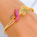 Gold bracelet with pink and green gemstones on a wrist against a neutral background