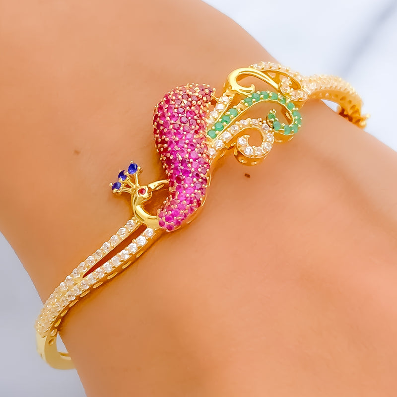 Gold bracelet with pink and green gemstones on a wrist against a neutral background