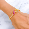 Gold bracelet with colorful stones on a wrist against a marble background