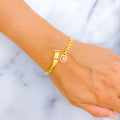 Gold bracelet with a pink gemstone on a wrist against a light background