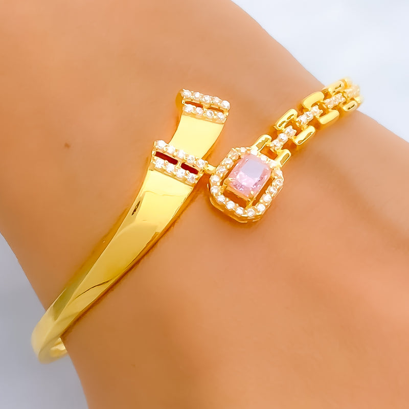 Gold bracelet with a pink gemstone on a wrist against a white background