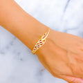 Gold bracelet with pink stones on a wrist against a marble background