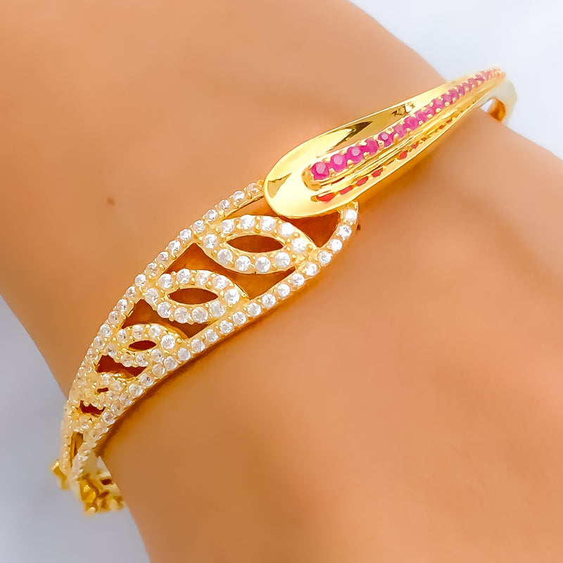 Gold bracelet with pink stones on a wrist against a neutral background