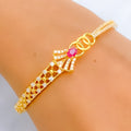 Gold bracelet with a pink gemstone on a wrist against a neutral background