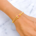 Gold bracelet with a red gemstone on a wrist against a light background
