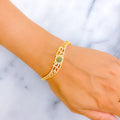 Gold bracelet with a green gemstone on a marble surface