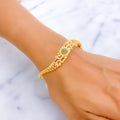 Gold bracelet with gemstones on a wrist against a marble background