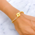 Gold bracelet with a floral design on a wrist against a marble background