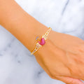Gold bracelet with a pink peacock gemstone on a wrist against a marble background
