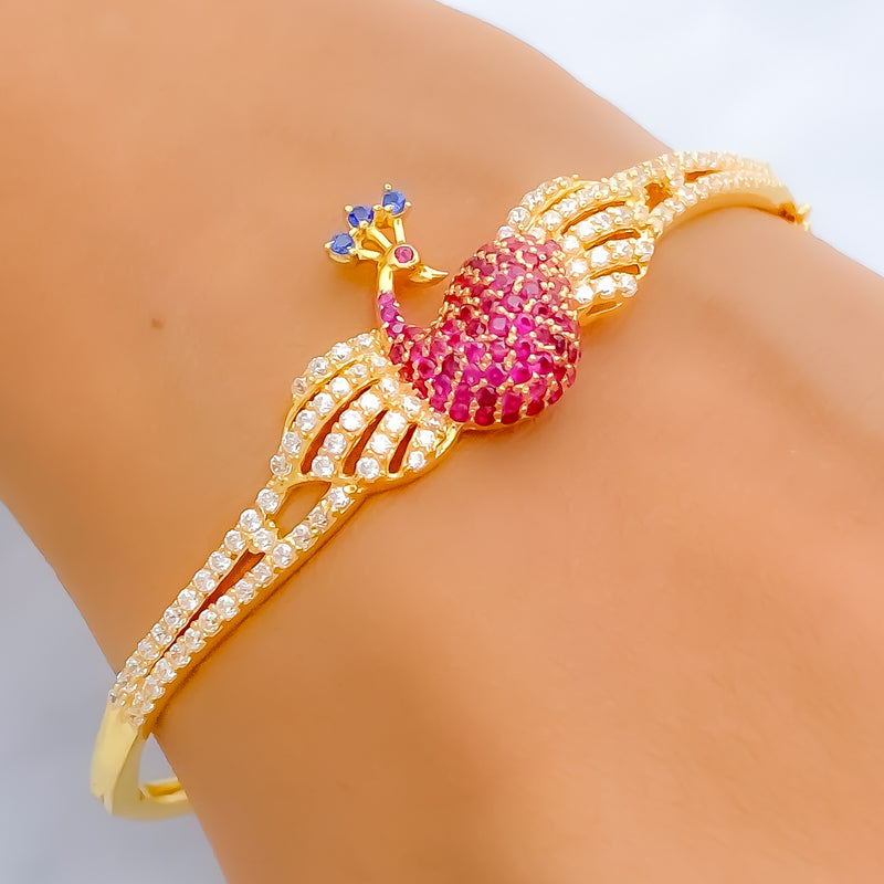 Gold bracelet with pink gemstone on a wrist against a neutral background