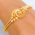 Gold bracelet with intricate design on a person's wrist against a neutral background