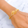 Gold bracelet with intricate design on a wrist against a white background