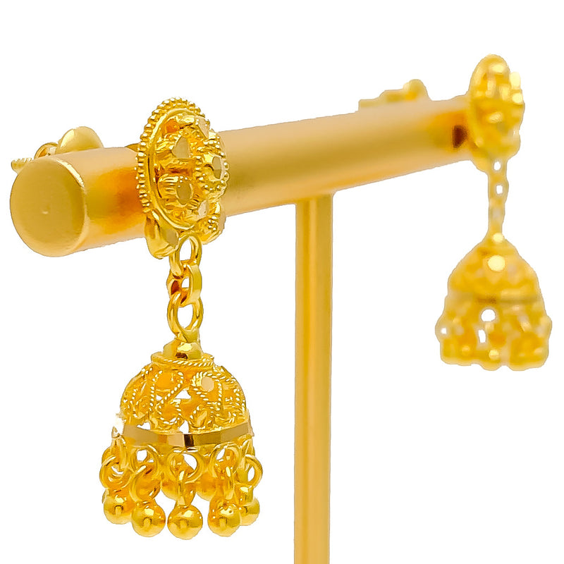 Gold earrings on a display stand with a white background
